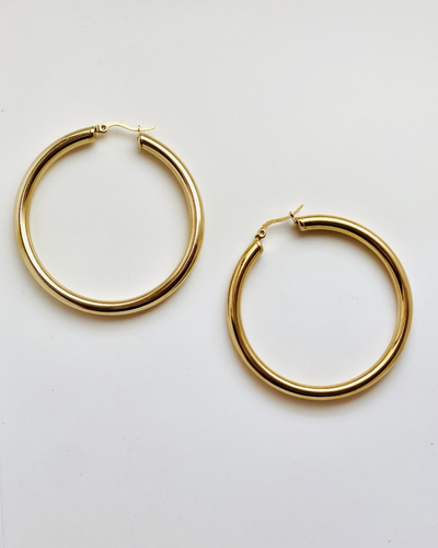 Pair of hooped gold earrings on beige background
